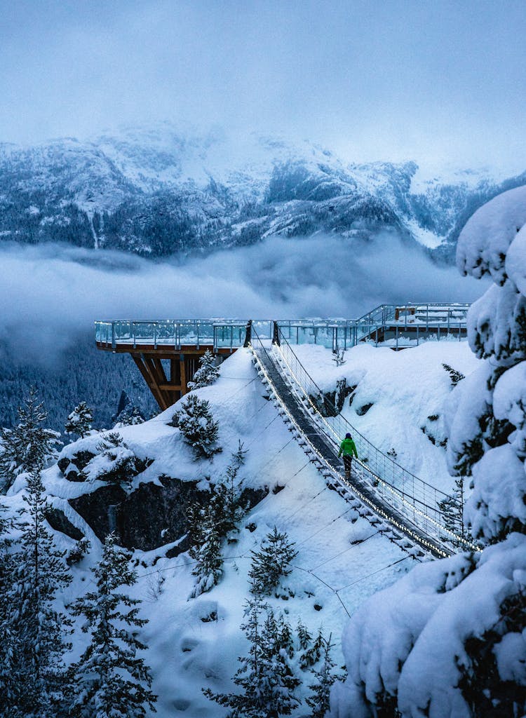 A breathtaking view of a snowy footbridge amidst mountains in British Columbia during winter.